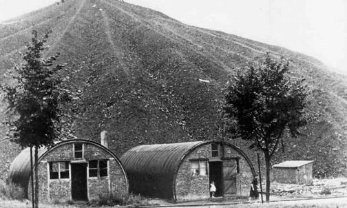Le misere baracche dei minatori, prima abitate dai prigionieri di guerra. Sullo sfondo una montagna di carbone. Archivio Nino Di Pietrantonio
